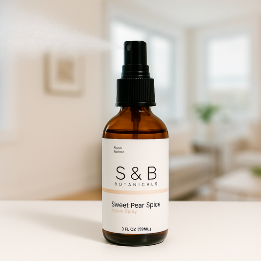 S&B Botanicals Room Spray amber glass bottle displayed on white surface in bright minimalist living room, 2oz water-based phthalate-free fragrance spray for any space