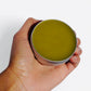 Comfrey salve 2 oz tin held in hand showing size and packaging of natural herbal balm