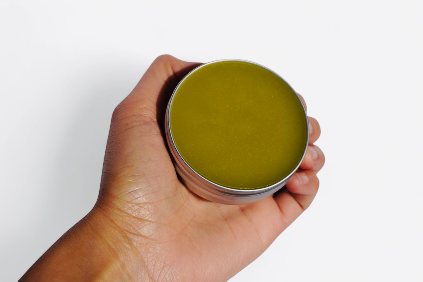 Comfrey salve 2 oz tin held in hand showing size and packaging of natural herbal balm