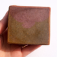 Hand holding unwrapped S&B Botanicals Toasted Matcha Latte Soap Bar showing natural earthy green-brown texture with purple mica shimmer, handmade in small batches in Washington​​​​​​​​​​​​​​​​