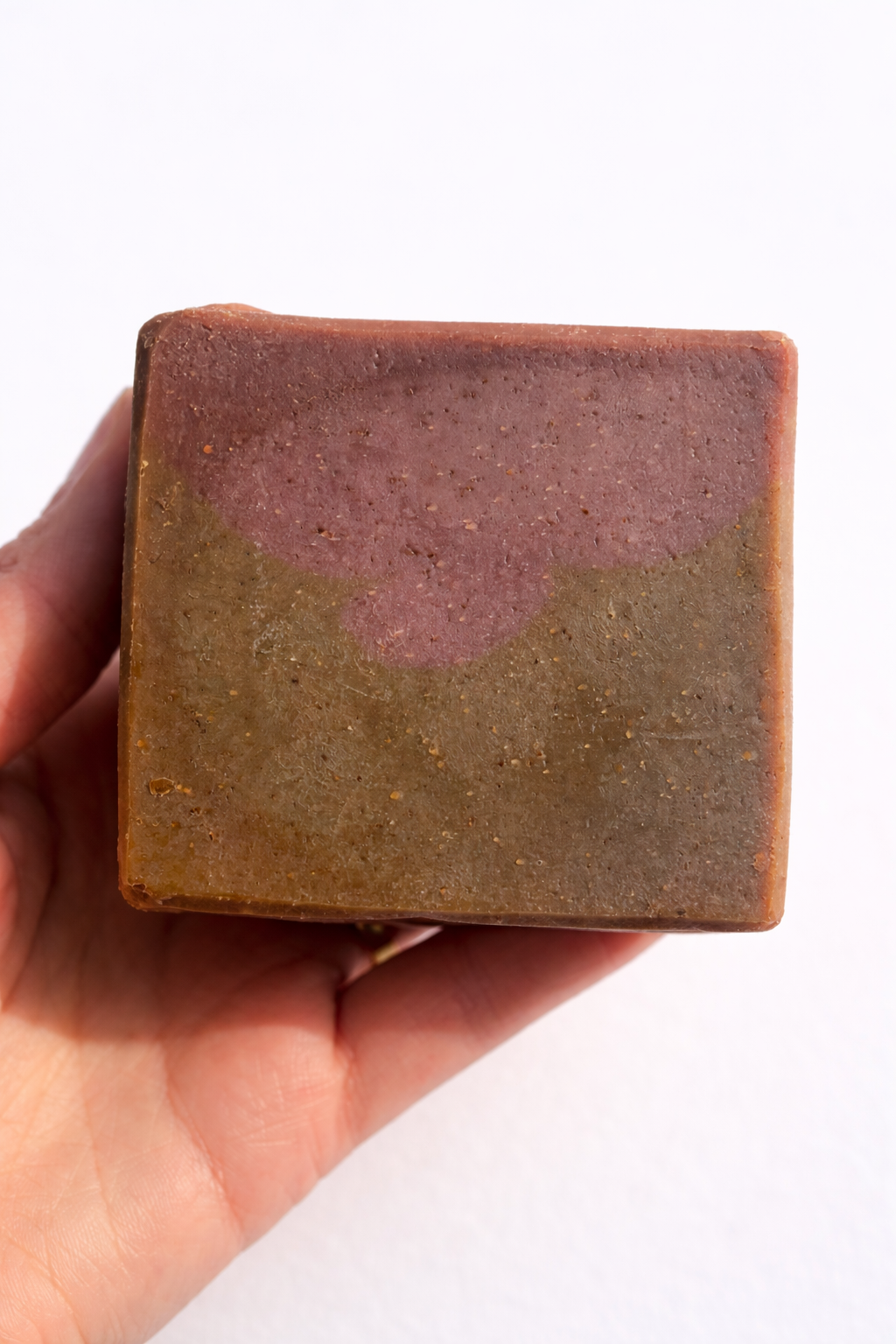 Hand holding unwrapped S&B Botanicals Toasted Matcha Latte Soap Bar showing natural earthy green-brown texture with purple mica shimmer, handmade in small batches in Washington​​​​​​​​​​​​​​​​