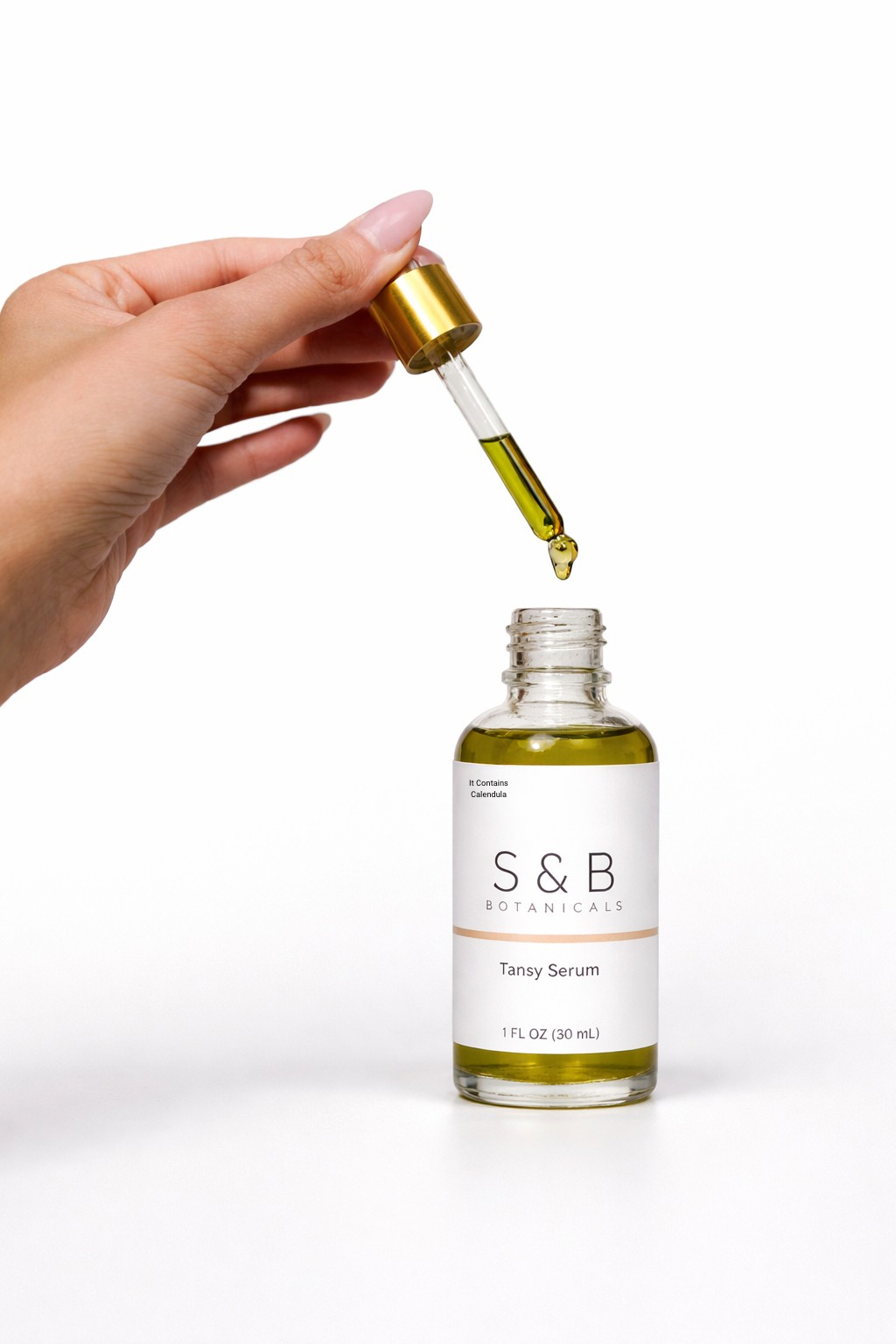 Close-up of dropper dispensing blue tansy face serum showing lightweight facial oil texture
