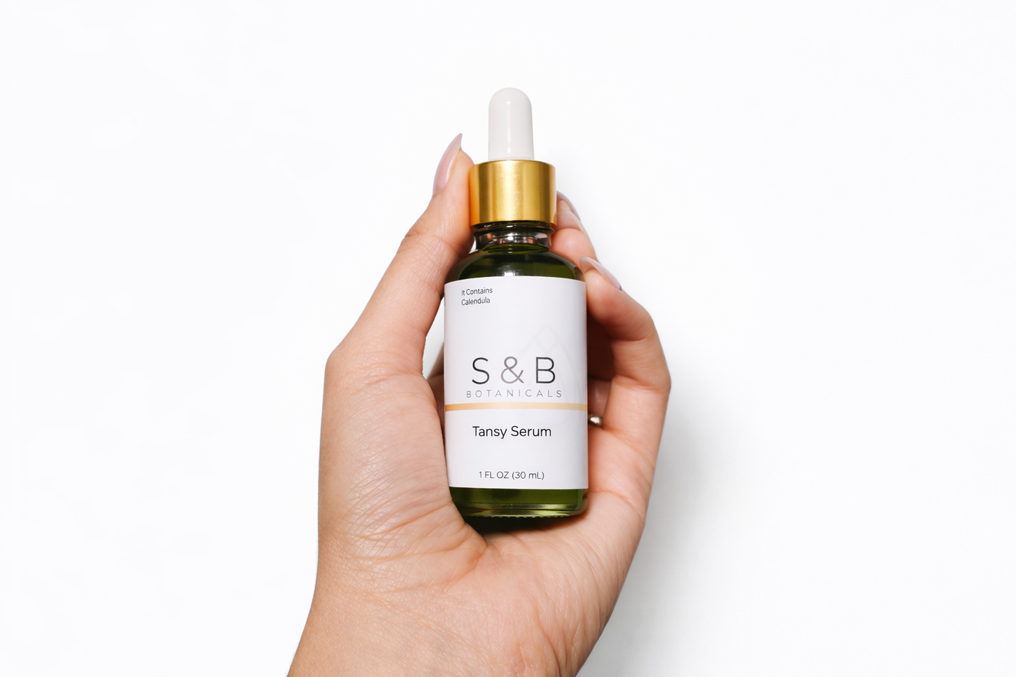 Hand holding blue tansy face serum bottle for size reference