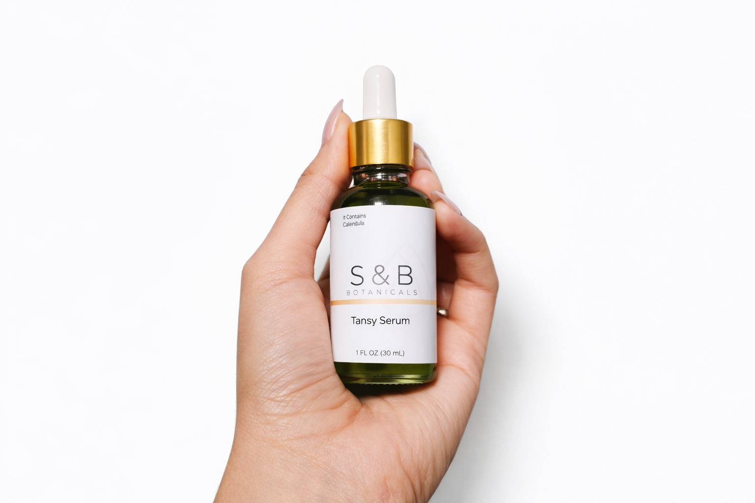Hand holding blue tansy face serum bottle for size reference