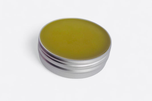 Close-up of comfrey salve texture showing smooth herbal balm consistency in metal tin